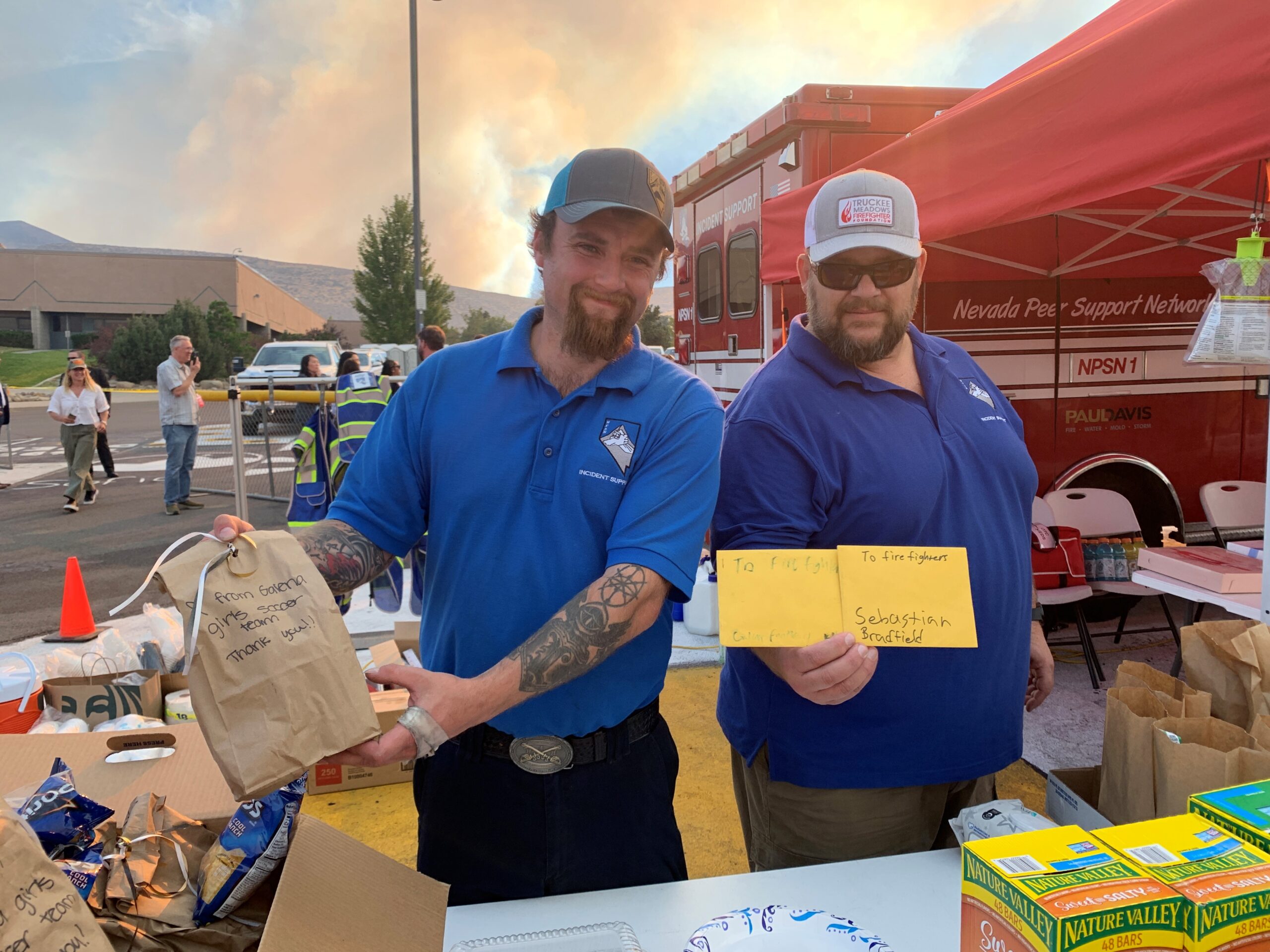 Photo of two disaster relief workers holding a thank-you note and bags of food.